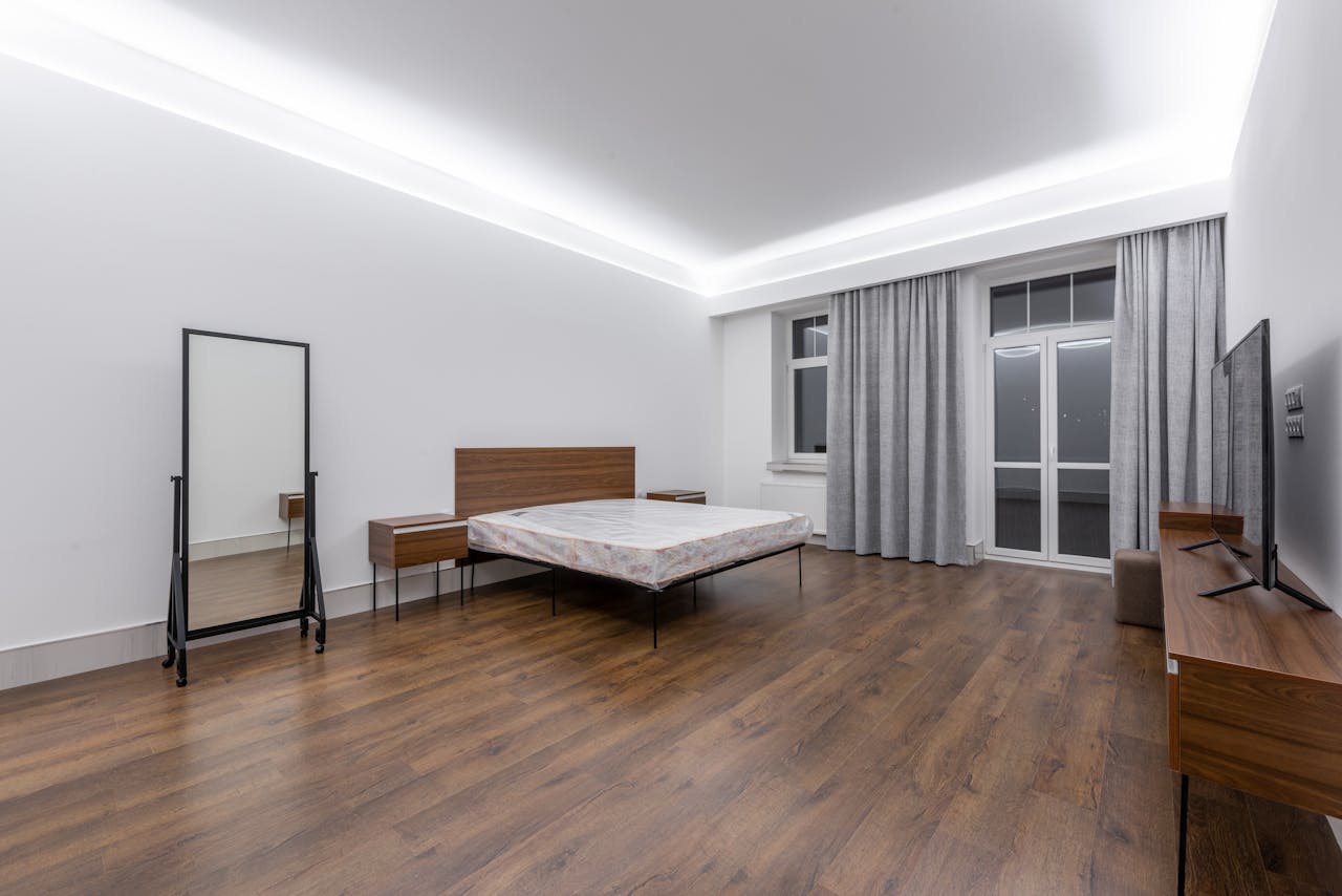 Elegant and spacious minimalist bedroom with wood flooring and contemporary furnishings.